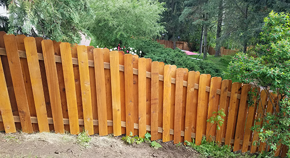 Curved wood picket fence following a landscaped slope