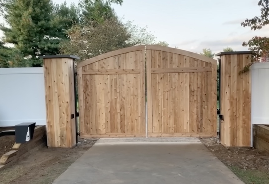 Large wood driveway gate between matching wood posts